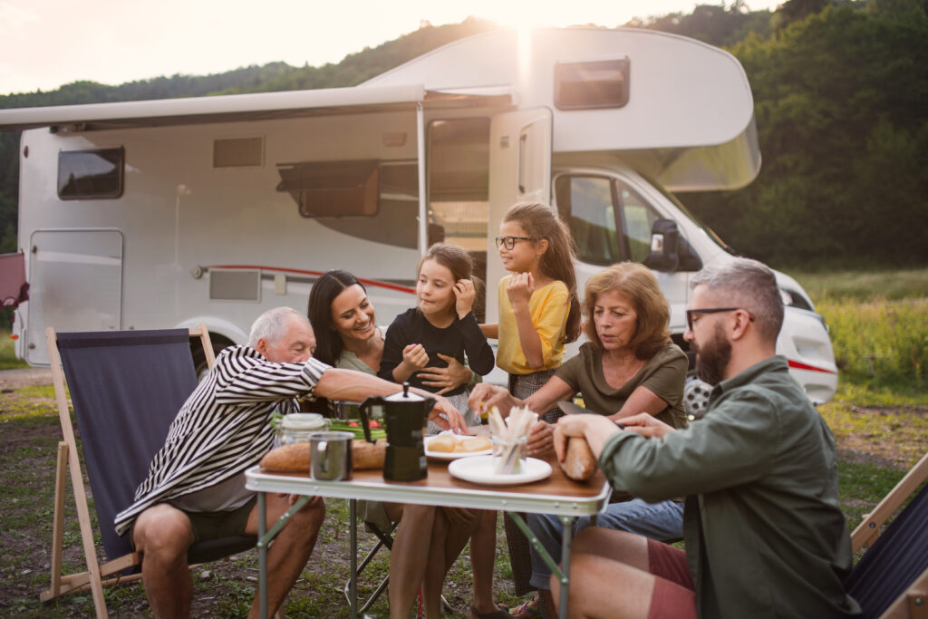Famille autour d'une table devant un camping-car